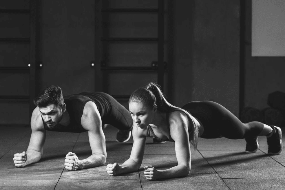 Un hombre y una mujer haciendo la plancha abdominal como parte del método de  EMA