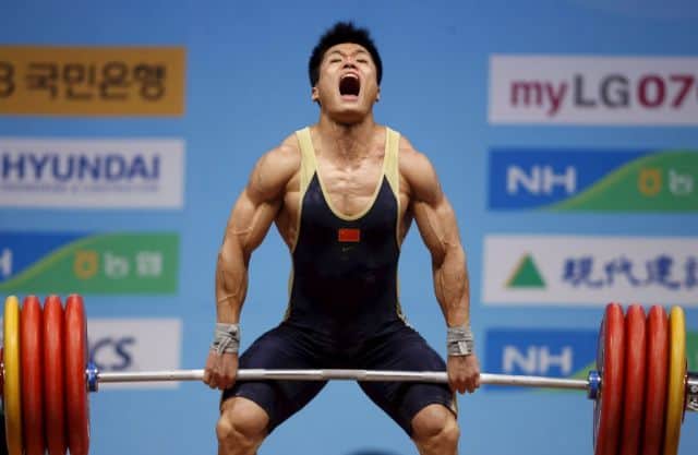 Atleta de halterofilia realizando un levantamiento en una competición, con expresión de esfuerzo poniendo a prueba el  con periodización ondulada diaria